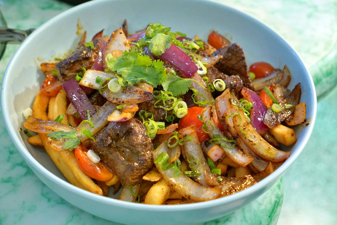 Lomo saltado, filet mignon, wood grilled and sautéed with cherry tomatoes and onions served over fries